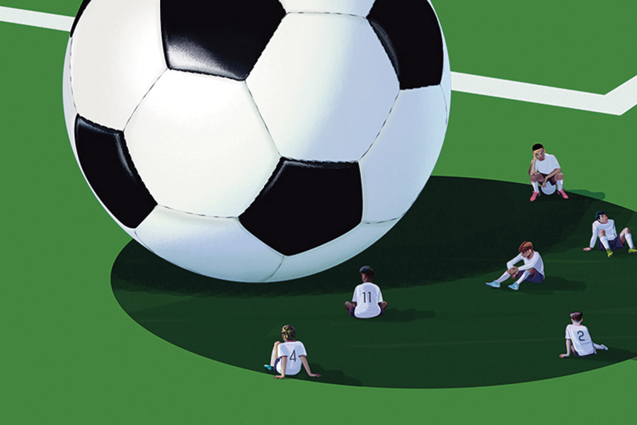 Soccer Players sitting in the shadow of a large soccer ball
