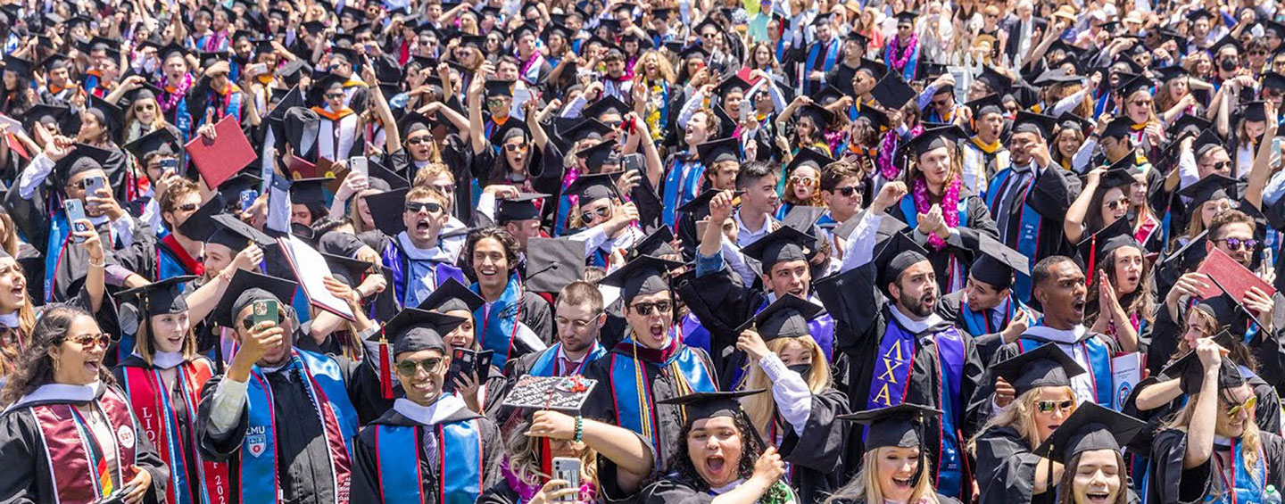 A sea of graduating students standing up and cheering