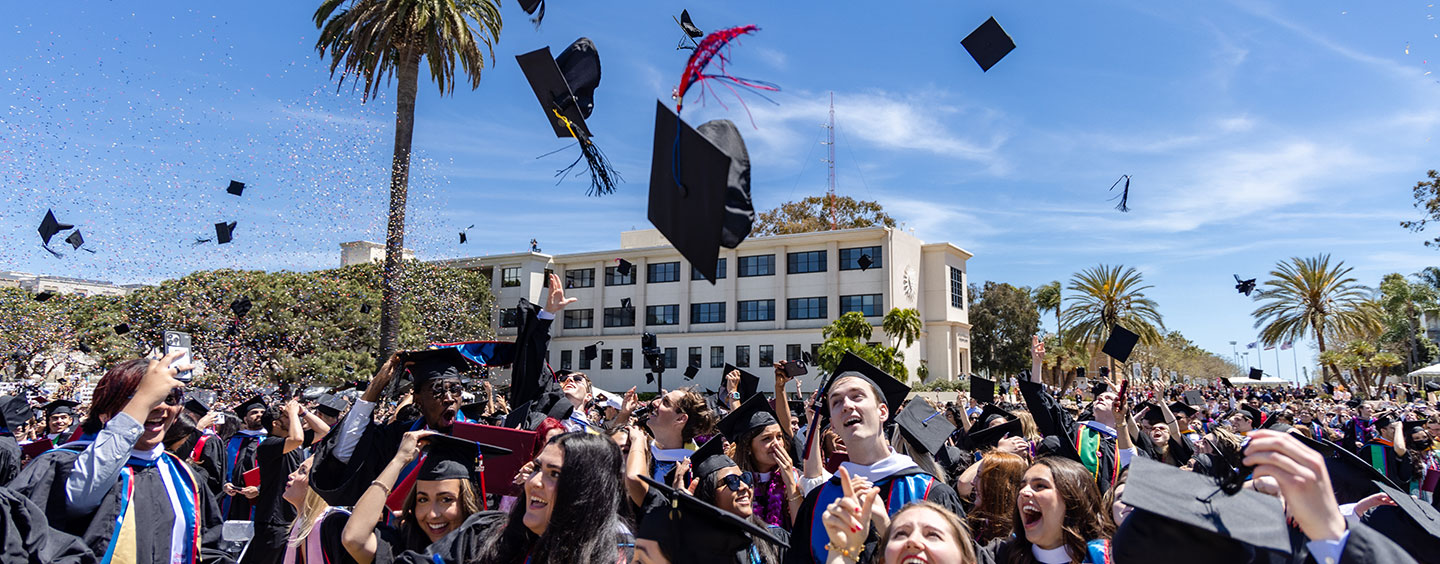 A sea of new graduates throwing their caps in the air upon completion of commencement as confetti rains down